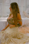 Woman in a lace dress sitting in a softly lit room with white curtains.