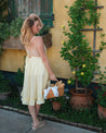 Woman in a yellow dress standing in a garden with plants and flowers.