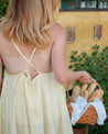 Woman in a yellow dress holding a basket of bread outdoors. butter yellow upcycled dress made from a vintage tablecloth
