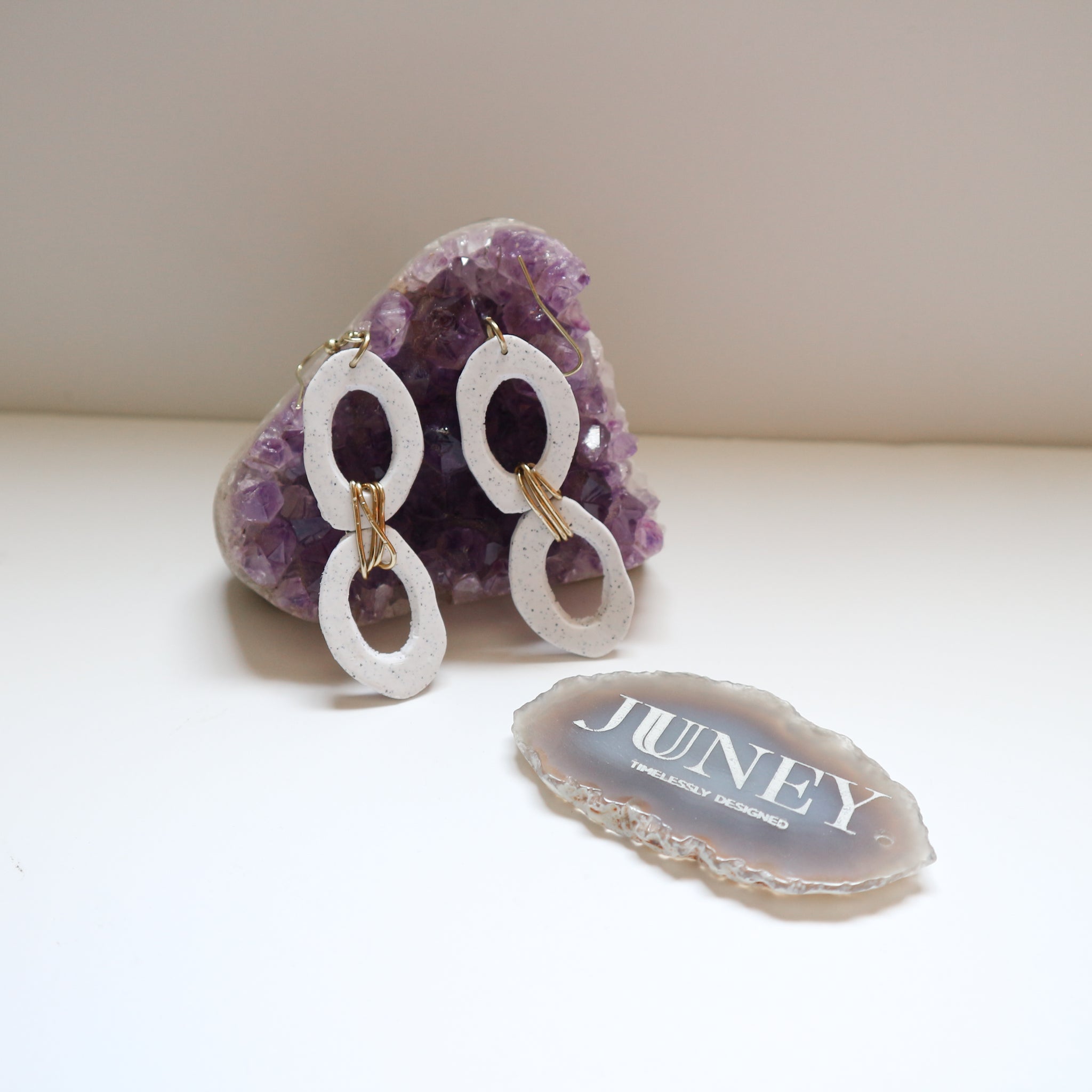 earrings hanging from crystal rock next to engraved agate