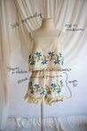 Mannequin wearing a dress with floral patterns and measurements on a white background