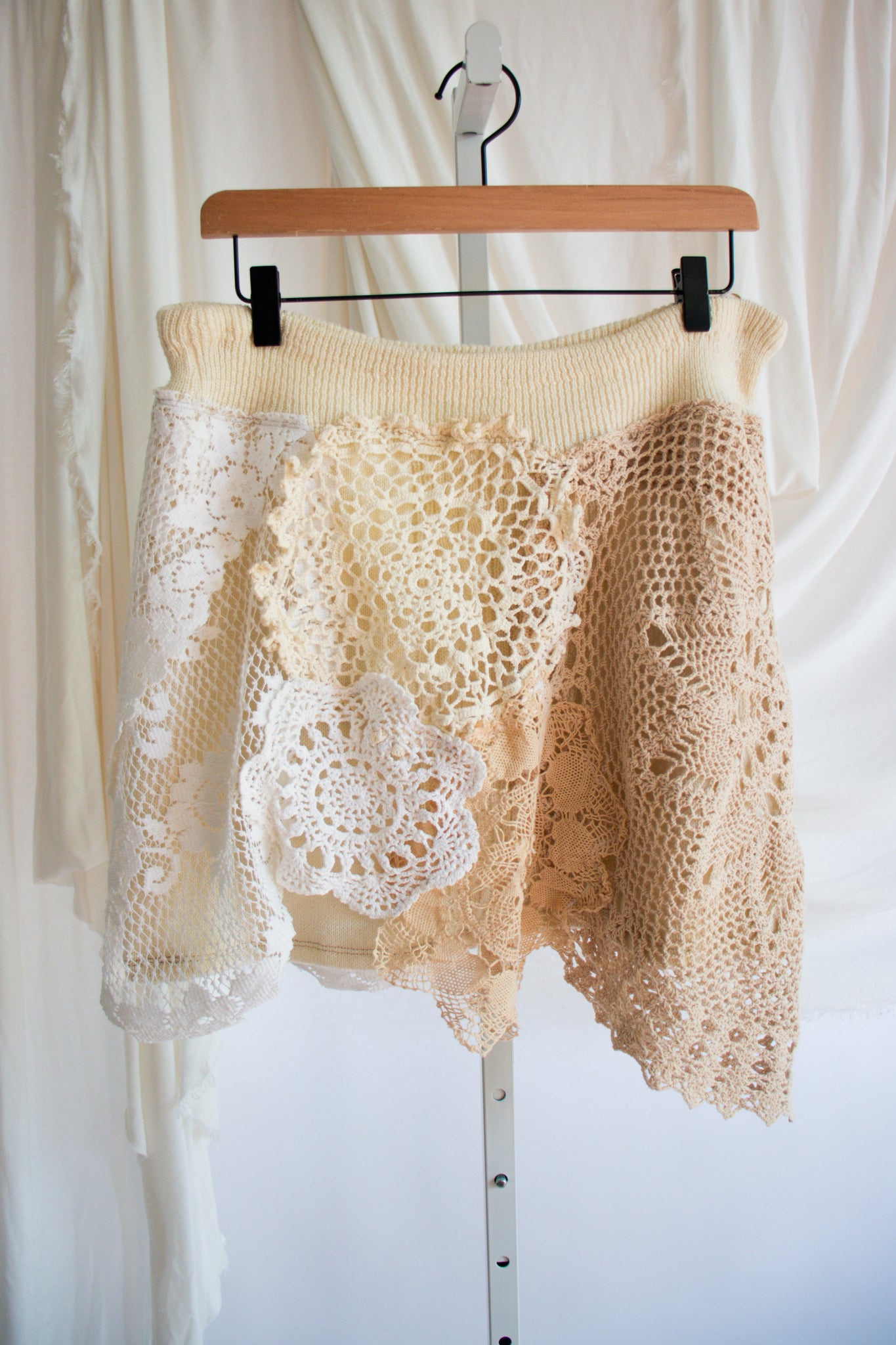 Skirt lace detailing on a hanger against a white curtain background