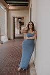 woman wearing blue dress leaning on wall